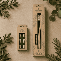 Venora dental care products in packaging on a textured surface with green leaves.
